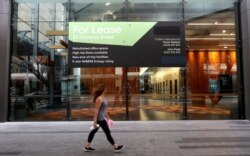 A woman walks past a lease sign at a commercial building in Sydney, Sept. 2, 2020. Australia's economy has suffered its sharpest quarterly drop since the Great Depression because of the COVID-19 pandemic.
