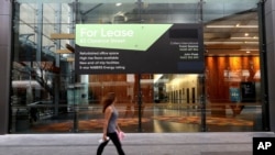 A woman walks past a lease sign at a commercial building in Sydney, Wednesday, Sept. 2, 2020. Australia's economy has suffered its sharpest quarterly drop since the Great Depression.