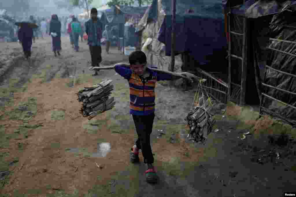 یک پسر بچه آواره روهینگیا در یک صبح زود در حال حمل هیزم در اردوگاه پناهندگان در بنگلادش &nbsp;