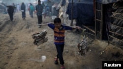 Seorang anak pengungsi Rohingya mengangkut kayu bakar di kamp "Burma Para" dekat Cox's Bazar, Bangladesh. Musim dingin telah tiba di sekitar kamp pengungsi dan mengancam para pengungsi akan menderita akibat kedinginan. 