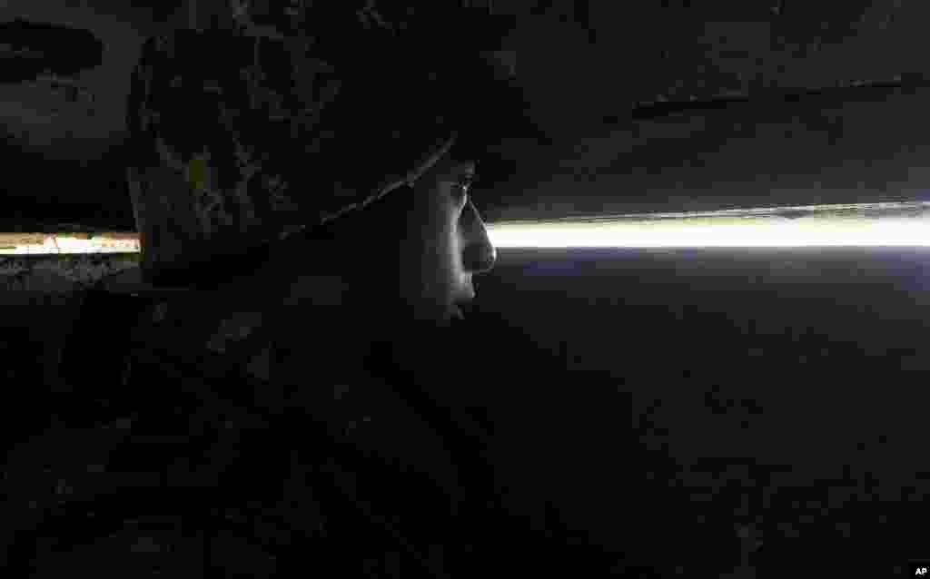 An Ethnic Armenian soldier looks through the gap toward Azerbaijan&#39;s positions from a dugout at a fighting position on the front line, during a military conflict against Azerbaijan&#39;s armed forces in the separatist region of Nagorno-Karabakh, Wednesday, Oc