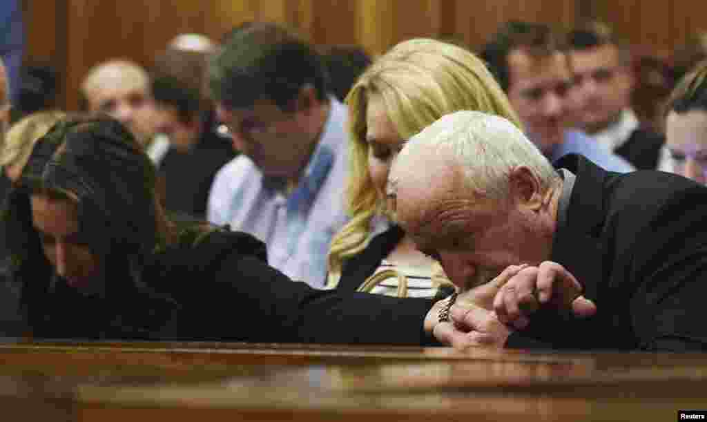 Henke Pistorius kisses the hand of his daughter Aimee Pistorius during the verdict for his son Oscar Pistorius at the North Gauteng High Court in Pretoria, Sept. 11, 2014.&nbsp;