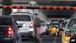 A Chinese beggar walks amongst traffic asking for a handout in Beijing, China. China's inflation rate edged lower in September, giving Chinese leaders leeway to stimulate the economy as U.S. and European growth slows, October 14, 2011.