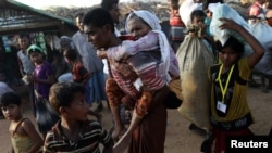 Rohingya refugee Suray Khatun, 70, is carried by her son Said-A-Lam, 38, as they enter Kutupalong refugee camp, near Cox's Bazar, Bangladesh a day after crossing the Myanmar border, November 20, 2017
