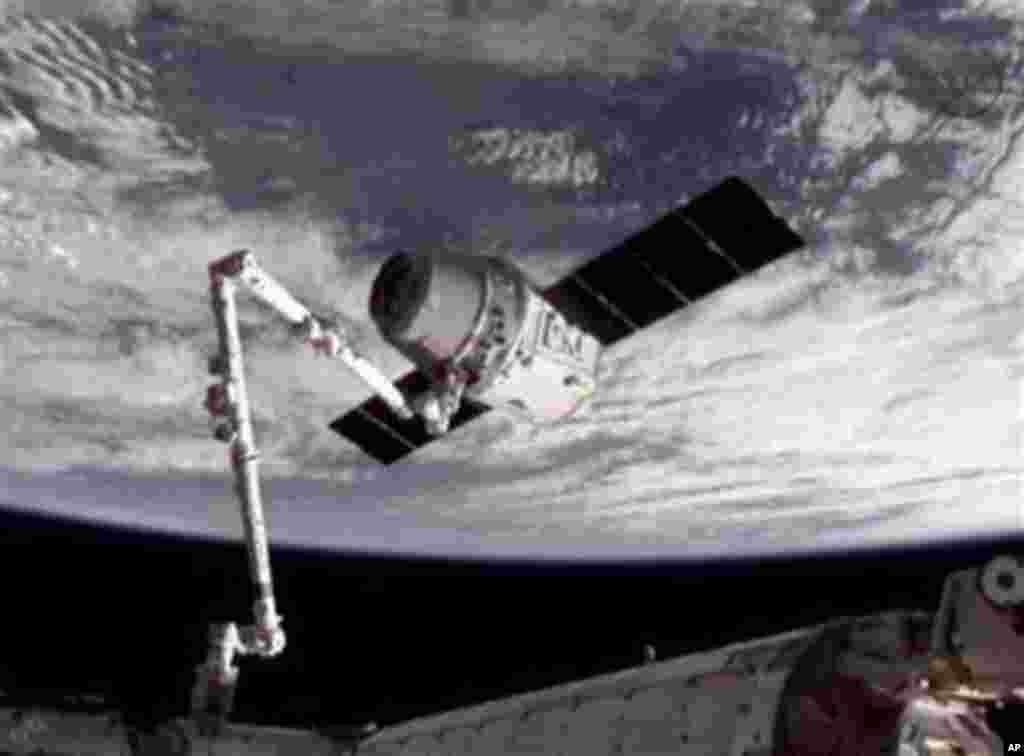 This image provided by NASA-TV shows the SpaceX Dragon commercial cargo craft, top, after Dragon was grappled by the Canadarm2 robotic arm and connected to the International Space Station, Friday, May 25, 2012. Dragon is scheduled to spend about a week do