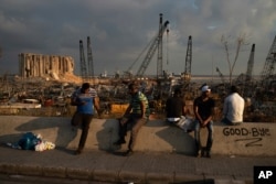People sit near the site of last week's explosion that hit the seaport of Beirut, Lebanon, Aug. 11, 2020.