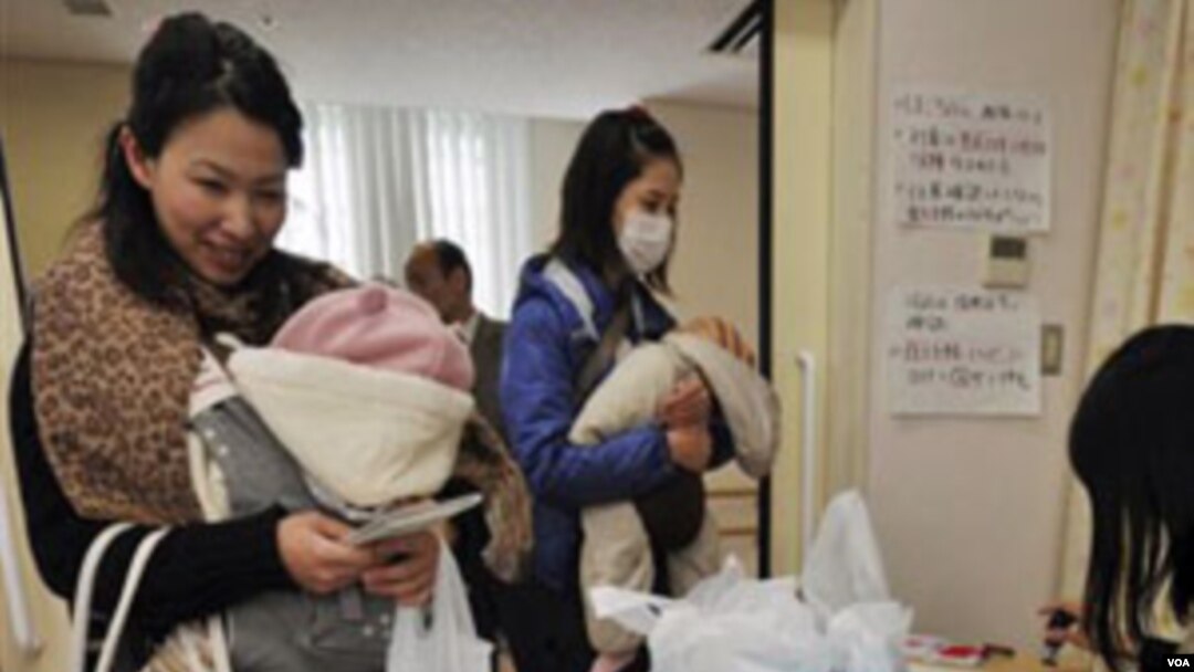 Ibu-ibu dengan anak balita mendapat air minum dalam kemasan di sebuah klinik di Tokyo, Kamis (24/3).
