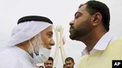 Hassan Mushaima, a Bahraini rights activist and a prominent Shi'ite opposition leader, wears a mask against tear gas as he is greeted by an anti-government demonstrator at Pearl roundabout in Manama, Bahrain, March 13, 2011