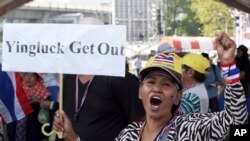 Seorang demonstran anti-pemerintah memegang spanduk dan meneriakkan yel-yel dalam pawai di sekitar Tugu Kemenangan, Bangkok, Thailand (21/1).