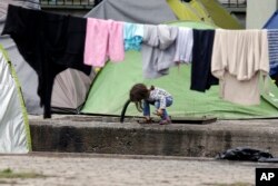 A child drinks water from a pipe on the platform of a train station which was turned into a makeshift camp crowded by migrants and refugees at the northern Greek border point of Idomeni, Greece, May 2, 2016.