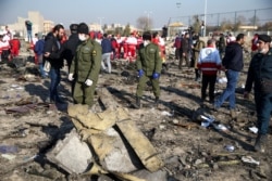 FILE - Security officers and Red Crescent workers are seen at the site where a Ukraine International Airlines plane crashed after takeoff from Iran's Imam Khomeini airport, on the outskirts of Tehran, Iran, Jan. 8, 2020.