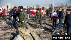 FILE - Security officers and Red Crescent workers are seen at the site where the Ukraine International Airlines plane crashed after take-off from Iran's Imam Khomeini airport, on the outskirts of Tehran, Jan. 8, 2020.