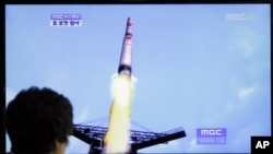 Una mujer en Corea del Sur mira el lanzamiento del cohete por parte de Corea del Norte, un minuto después la nave se despedazó en el aire.