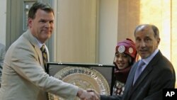 Canada's Foreign Minister John Baird (L) exchanges gifts with the head of Libya's National Transitional Council Mustafa Abdel Jalil, during his first visit to the rebel-held city of Benghazi, June 27, 2011
