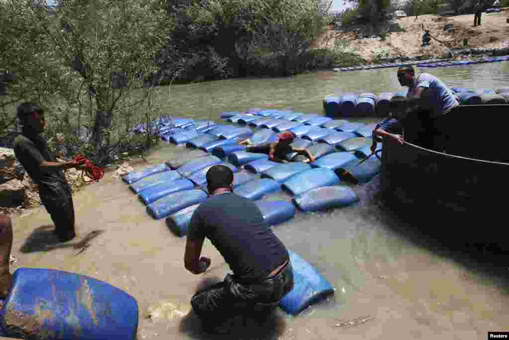 A group of men smuggle diesel fuel from Syria to Turkey across the Al-Assi River in Darkush town, Idlib countryside, hoping to sell it at a higher price, May 26, 2013.