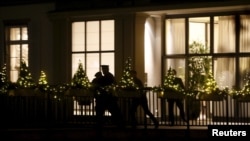 People are silhouetted outside the Baur au Lac hotel where Swiss police arrested FIFA officials, in Zurich, Switzerland, Dec. 3, 2015.