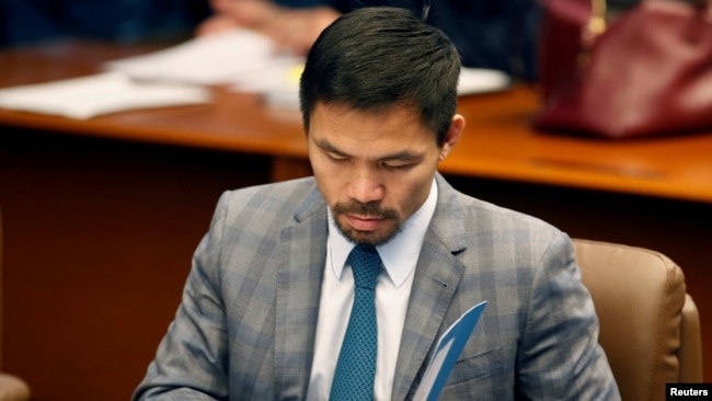 FILE - Philippine Senator and boxing champion Manny Pacquiao reads his briefing materials as he prepares for the Senate session in Pasay city, Metro Manila, Philippines, Sept. 20, 2016.