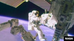 FILE - Astronaut Mike Hopkins works outside the International Space Station during a spacewalk, December 24, 2013, in this still image taken from video courtesy of NASA. Two NASA astronauts floated outside the International Space Station on Tuesday for a second 