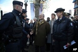 French Interior Minister Bruno Le Roux, center, shakes hand with police officers during a visit to see the police presence securing the Champs Elysees, in Paris, Sunday, Dec. 11, 2016.