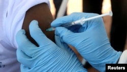 FILE - A World Health Organization worker administers a vaccination during the launch of a campaign aimed at beating an outbreak of Ebola in the port city of Mbandaka, Democratic Republic of the Congo, May 21, 2018.