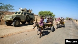Somali civilians pass by Ugandan soldiers serving with the African Union Mission in Somalia (AMISOM) in the central Somali town of Buur Hakaba, in this handout photograph taken and provided by the African Union-United Nations Information Support Team (AU-