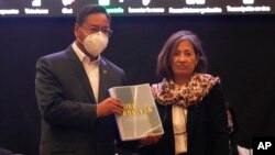 El presidente de Bolivia, Luis Arce, muestra el informe de expertos de la CIDH sobre los sucesos de 2019 junto a la representante del grupo, Patricia Tappata, en La Paz, Bolivia el 17 de agosto de 2021. 