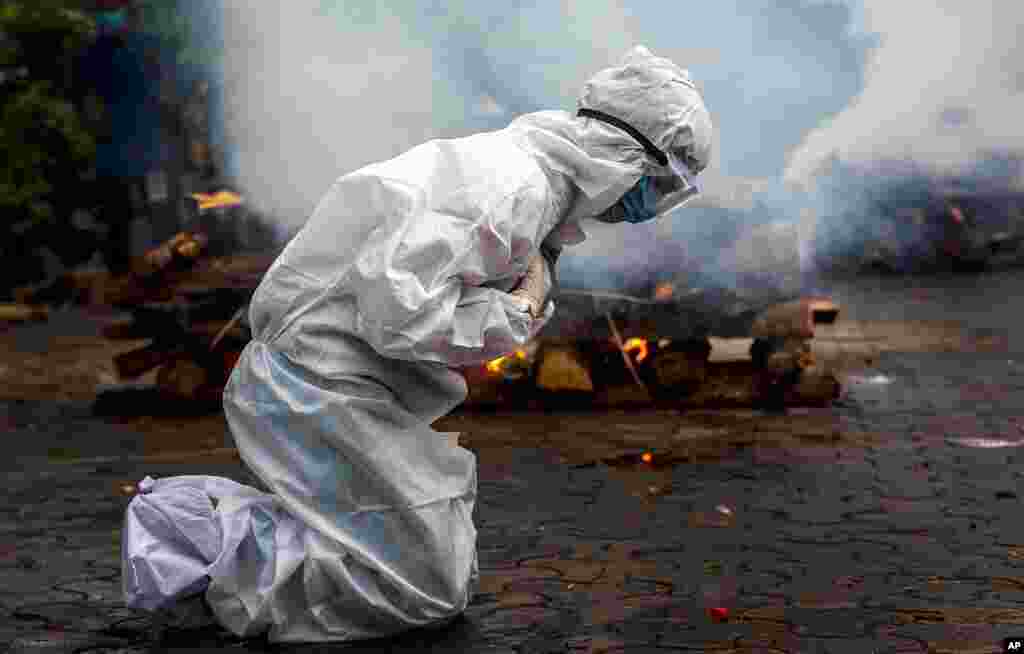 A woman breaks down as she prays before the cremation of a relative who died of COVID-19 in Gauhati, India. India on Friday crossed the grim milestone of more than 400,000 people lost to the coronavirus. 