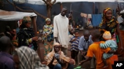 FILE - Muslim refugees listen to a radio at the Catholic church in Carnot, Central African Republic, where they are taking shelter from Christian militants, April 16, 2014.
