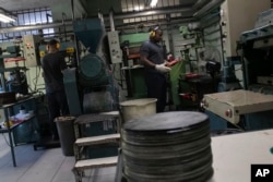 Operators work in the pressing stage of vinyl records production at the Polysom factory in Belford Roxo, Brazil, Tuesday, April 16, 2024. Vinyl’s comeback in Brazil follows a global trend over the last 15 years. (AP Photo/Bruna Prado)