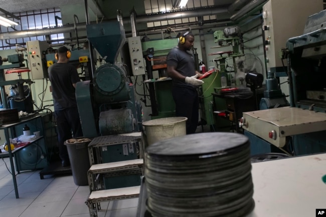 Operators work in the pressing stage of vinyl records production at the Polysom factory in Belford Roxo, Brazil, Tuesday, April 16, 2024. Vinyl’s comeback in Brazil follows a global trend over the last 15 years. (AP Photo/Bruna Prado)