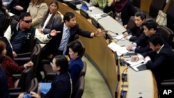 North Korean defectors, left, argue with North Korean diplomats, right, at United Nations headquarters as the diplomats try to make a statement during a panel discussion on North Korean human rights abuses, April 30, 2015.