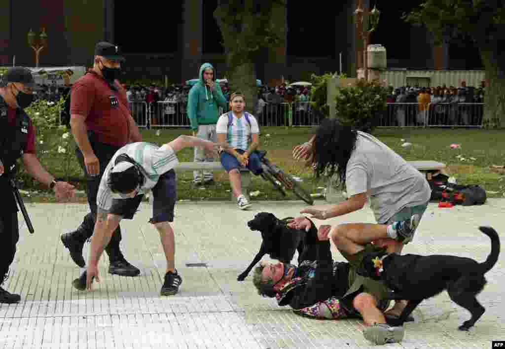 Fans fight to get a better position in line to enter the Government House to pay tribute to late football legend Diego Armando Maradona in Buenos Aires, Argentina.