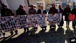 FILE - Members of the Srebrenica Women Union hold photographs of the 1995 Srebrenica massacre dead and missing in Tuzla, Bosnia, Nov. 11, 2017. The Balkan nations that fought bitter wars as the former Yugoslavia crumbled in the 1990s signed an agreement Nov. 6, 2018, to enhance their cooperation in identifying thousands of people still missing as a result of the conflicts.