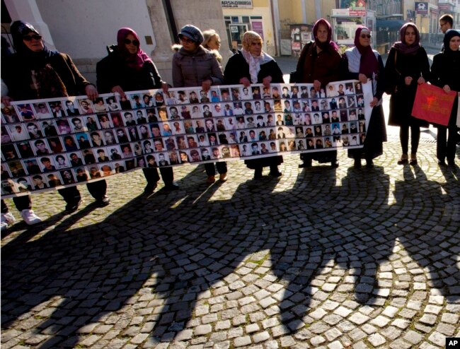 FILE - Members of the Srebrenica Women Union hold photographs of the 1995 Srebrenica massacre dead and missing in Tuzla, Bosnia, Nov. 11, 2017.