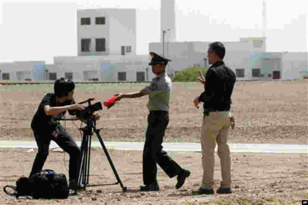6月16日，一名中国卫兵试图阻止外国记者在甘肃酒泉卫星发射基地&ldquo;神舟九号&rdquo;发射场附近拍摄。这一天，第四艘中国载人飞船&rdquo;神舟九号&ldquo;升空，随后成功与空间实验室雏形&rdquo;天宫一号&ldquo;对接。（美联社照片）