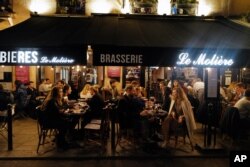 People enjoy food and drink on a terrace of a restaurant before the nightly coronavirus comes into effect, in Paris, France, Oct. 23, 2020.