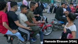 Une fille harcelée dans la rue par un groupe de jeunes hommes sur des motos, à Gizeh, en Égypte, le 15 juin 2018 (Hamada Elrasam/VOA)