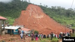 People inspect the damage after a mudslide in the mountain town of Regent, Sierra Leone, Aug. 14, 2017.