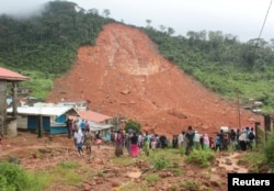 FILE - People inspect the damage after a mudslide in the mountain town of Regent, Sierra Leone, Aug. 14, 2017.