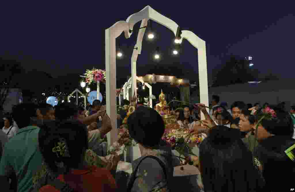 Buddhist Thais use lotus to apply holy water on the statues of Lord Buddha for their luck as part of a New Year celebrations in Bangkok, Thailand, Saturday, Dec. 31, 2011. (AP)