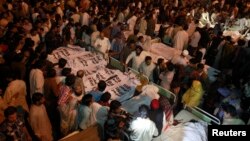 巴基斯坦與印度邊境的哇嘎鎮發生巨大爆炸後，巴基斯坦親屬聚集在死難者旁邊
