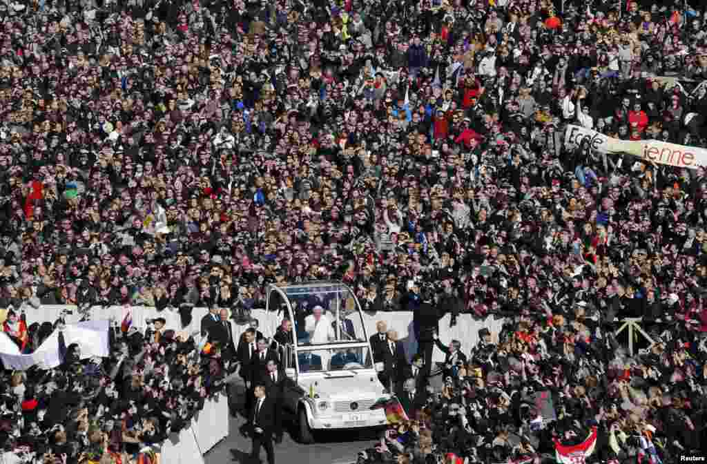 Pope Benedict XVI waves from his popemobile as he rides through a packed Saint Peter&#39;s Square at the Vatican during his last general audience. 