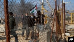 Palestinian demonstrators break a gate of the Israeli barrier during a protest against Israeli settlements in the outskirts of the village Kafr Thulth near the West Bank town of Qalqilya, Jan. 9, 2021.