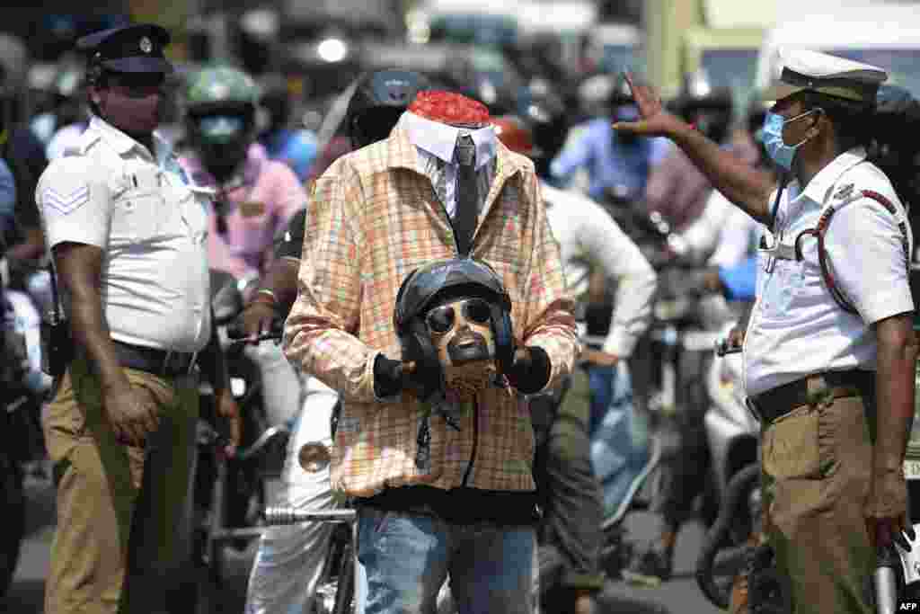 Police officers along with a volunteer (C) dressed up as a motorcyclist holding a mockup head with a helmet take part in a road safety awareness campaign, in Chennai , India.
