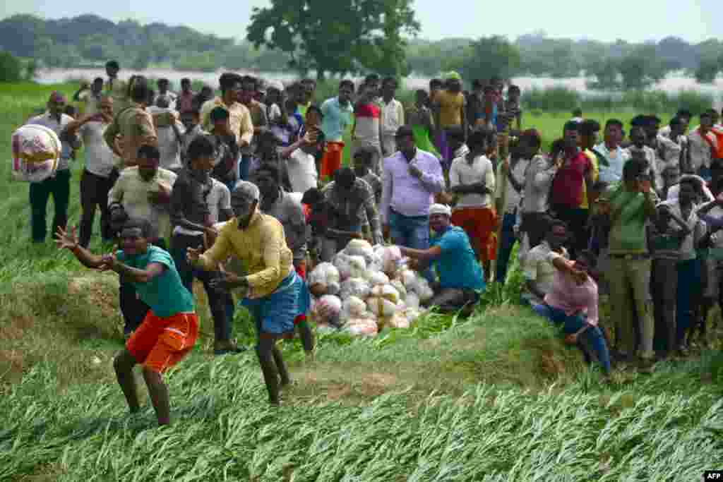 Flood-affected villagers receive relief supplies distributed by defense personnel from an Indian Air Force helicopter, near Allahabad.