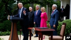 President Donald Trump speaks in the Rose Garden of the White House in Washington before signing an executive order aimed at easing an IRS rule limiting political activity for churches, May 4, 2017. From second from left are Cardinal Donald Wuerl, archbishop of Washington; Pastor Jack Graham; Paula White, senior pastor of New Destiny Christian Center in Apopka, Fla.; and Vice President Mike Pence.