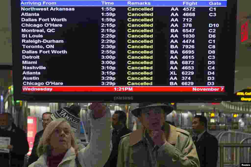 Travelers look at a monitor displaying cancelled flights in New York's LaGuardia airport, November 7, 2012.