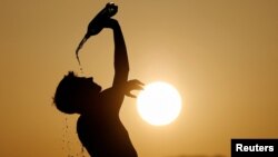 FILE - A runner cools down with water in Skopje, North Macedonia July 12, 2023.