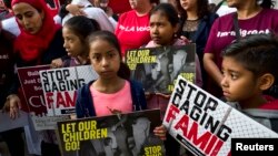 Children stand and hold protest signs during a rally in front of Federal Courthouse in Los Angeles on June 26, 2018. 