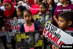 FILE - Children stand and hold protest signs during a rally in front of the U.S. Courthouse in Los Angeles, June 26, 2018.